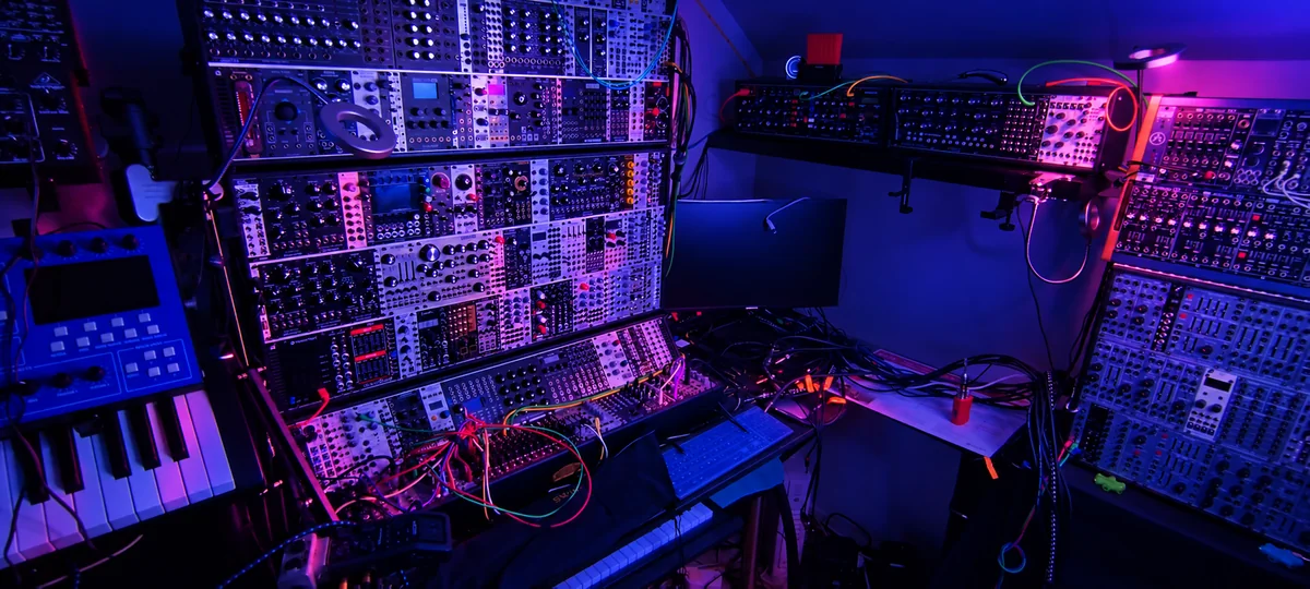 Vue du studio KNH et de ses synthétiseurs sous une lumière bleue et magenta